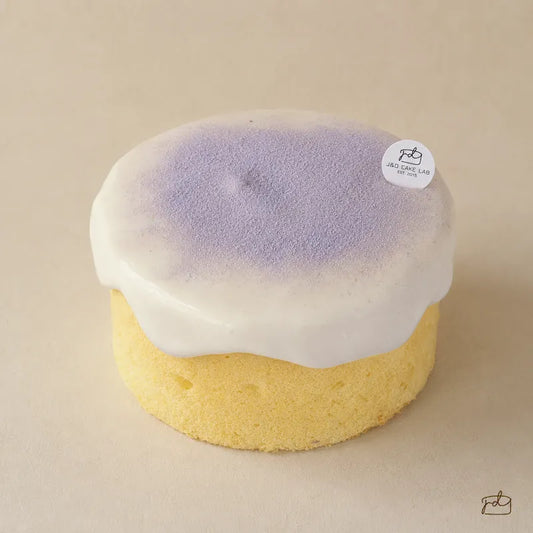 Front view of a taro cream cheese lava cake with chiffon sponge and flowing cream cheese topping