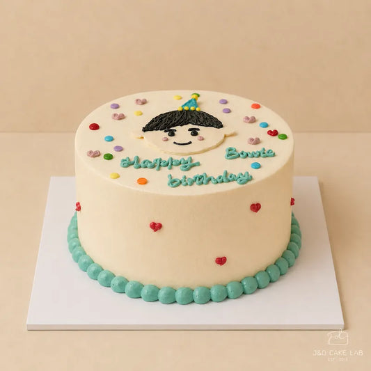 Front view of a little boy birthday cake with hand-piped face, blue cream border and red heart details