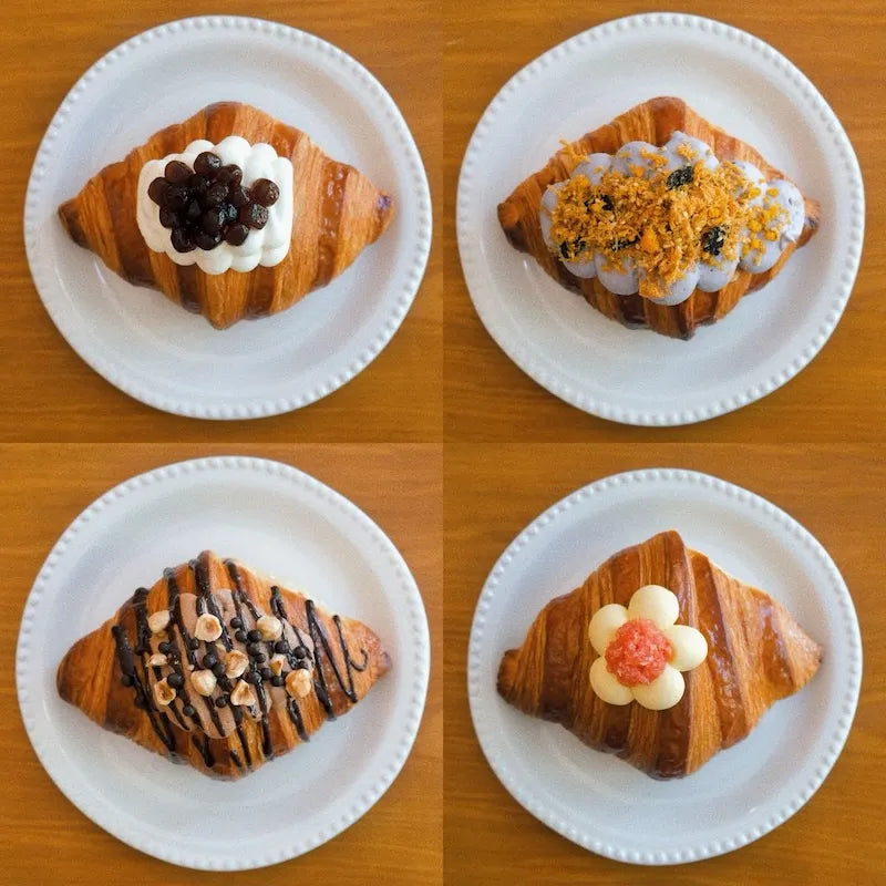 Four lava croissants on a wooden board: Signature Bubble Tea, Golden Lava Taro, Mango Pomelo Bliss and Double Choc Hazelnut.