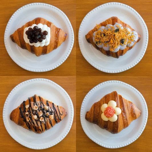 Four lava croissants on a wooden board: Signature Bubble Tea, Golden Lava Taro, Mango Pomelo Bliss and Double Choc Hazelnut.