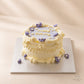 Side view of a lilac vintage cake with layered cream piping, purple flowers and pearl details