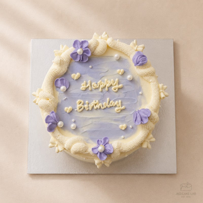 Top view of a lilac vintage birthday cake with personalised Happy Birthday writing