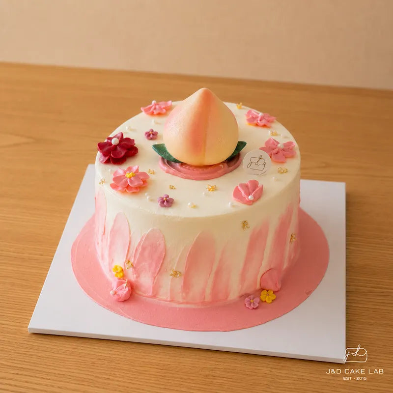 Front view of a Chinese ‘Longevity Peach’ Cake with ivory fresh cream, pink side details and floral decorations