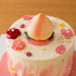 Close-up of the decorative ‘Longevity Peach’ topper surrounded by buttercream flowers and pearl details