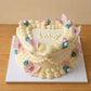 High-angle view of a heart-shaped gender reveal cake with vintage piping, pastel flowers and butterflies