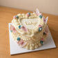 High-angle view of a heart-shaped gender reveal cake with vintage piping, pastel flowers and butterflies