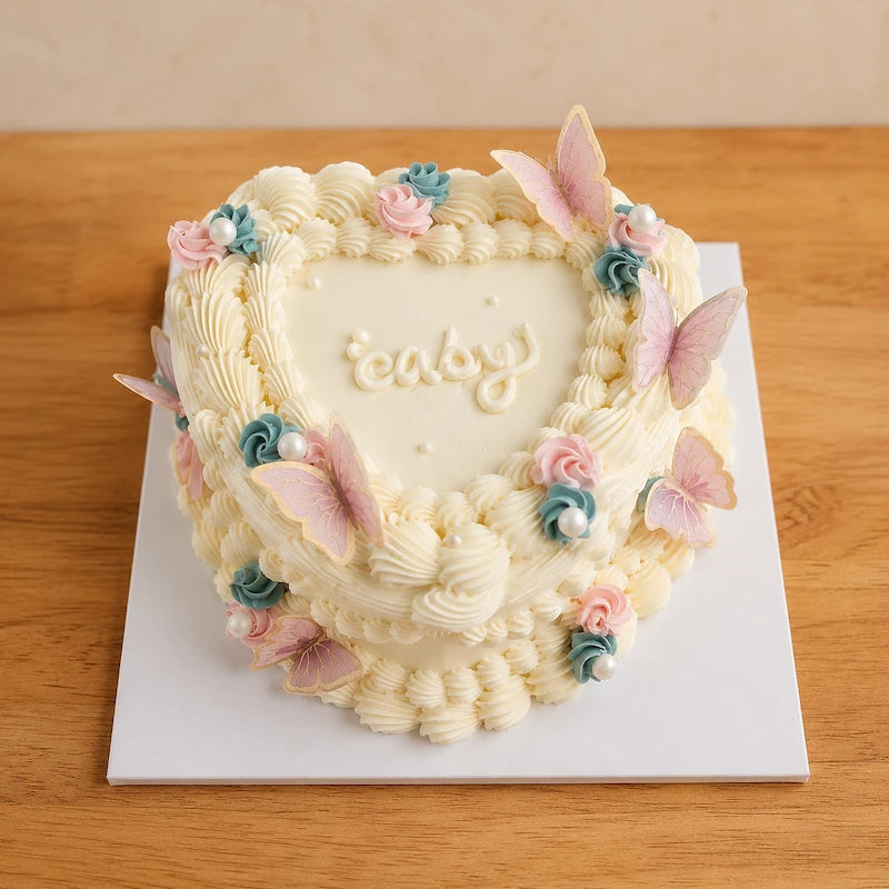 Front view of a vintage heart-shaped gender reveal cake with detailed cream piping and butterfly decorations