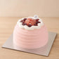 High-angle view of a blush guava cream cake topped with red grapes, guava pieces and white cream
