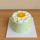 Side angle of mint green Daisy Smiley Face Cake with piped floral decorations