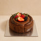 Three-quarter view of Chocolate Basque Burnt Cheesecake with rich baked chocolate exterior and berry decoration