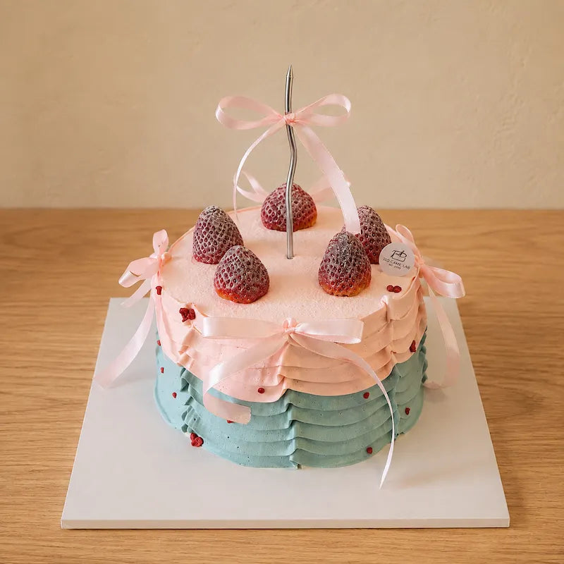 High-angle view of pastel Ribbon and Ruffles Cake topped with strawberries and ribbon details