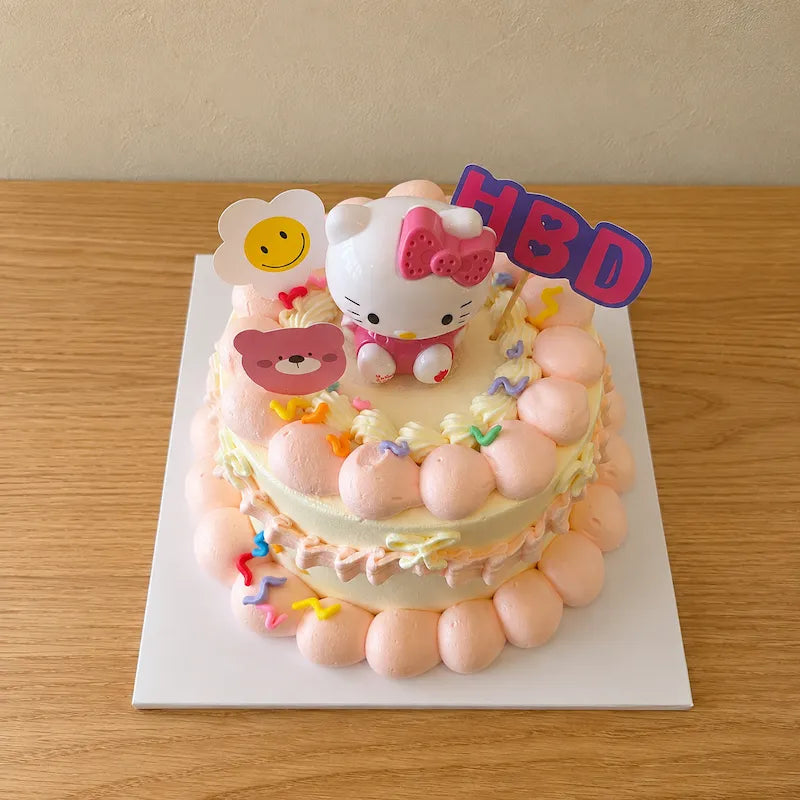 High-angle view of Vintage Hello Kitty Birthday Cake with character topper and pastel birthday decorations
