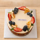 Top view of Basque burnt cheesecake with seasonal berries, citrus slices and cream decoration