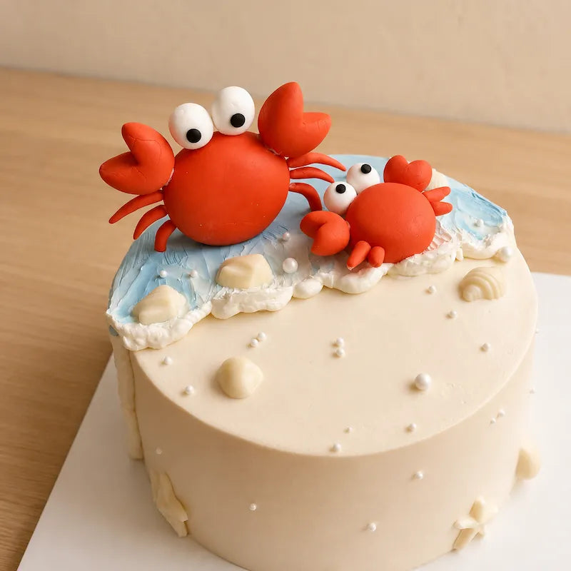 Close-up of two handmade fondant crabs sitting on blue buttercream ocean waves