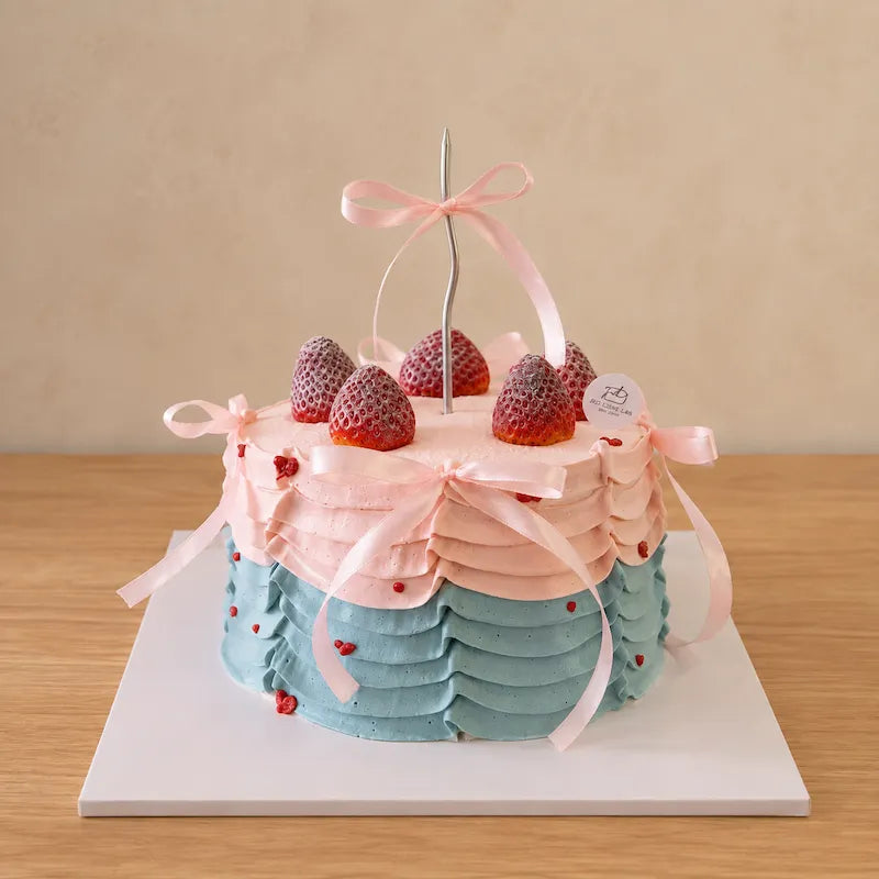 Three-quarter view of pastel birthday cake with layered pink and blue ruffles and ribbon bows