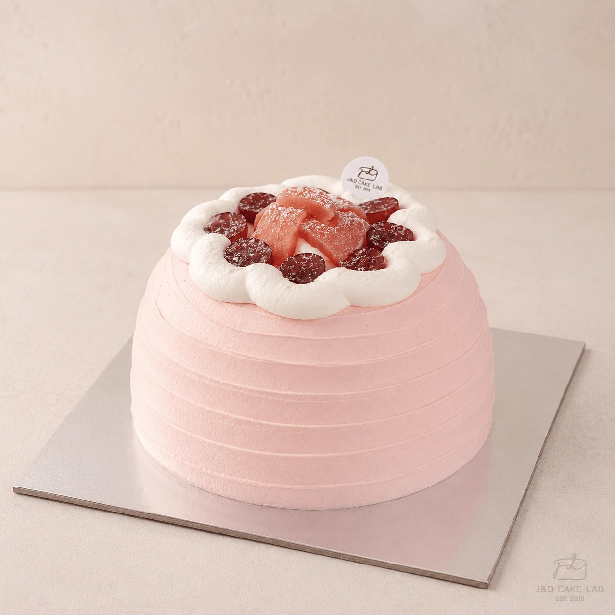 High-angle view of a blush guava cream cake topped with red grapes, guava pieces and white cream