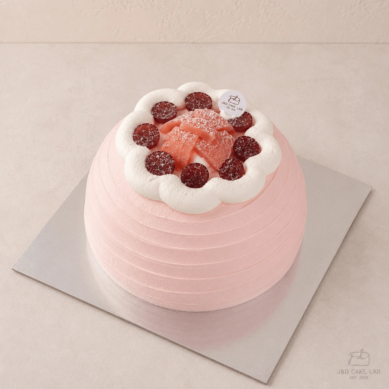 Front view of a pink guava cream cake with horizontal texture and red grape topping