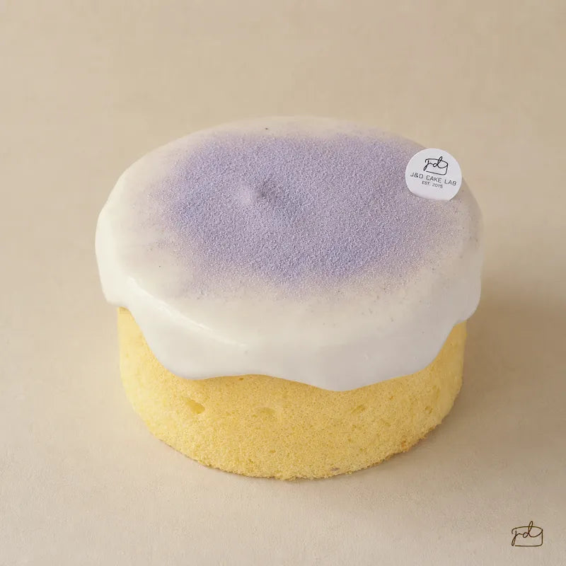 Front view of a taro cream cheese lava cake with chiffon sponge and flowing cream cheese topping