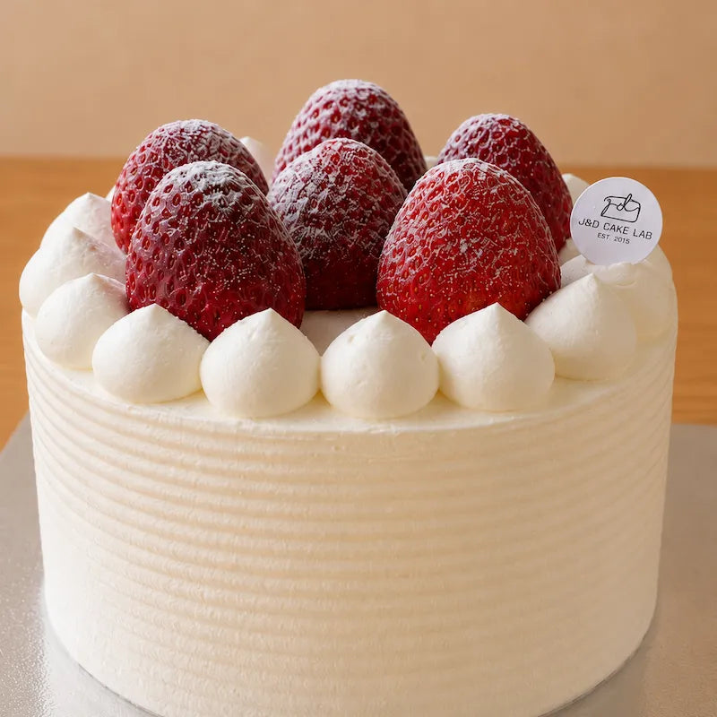 Close-up of whole strawberries, icing sugar and piped fresh cream on a Japanese style cake