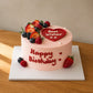 Three-quarter view of personalised seasonal fruit cake with red heart message plaque