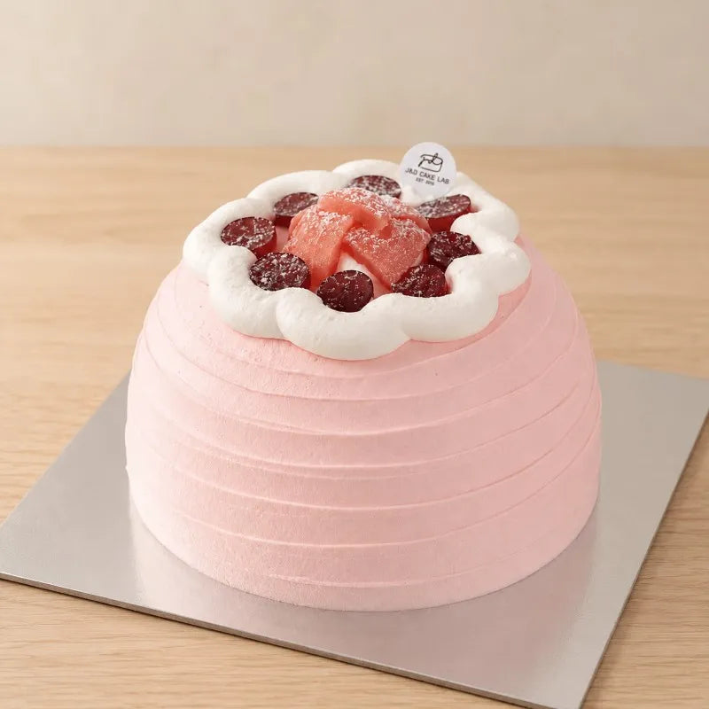 Front view of a pink guava cream cake with horizontal texture and red grape topping