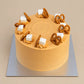 Thai Tea Velvet cake with orange cream, piped swirls, white cubes and golden pretzels on a silver cake board.