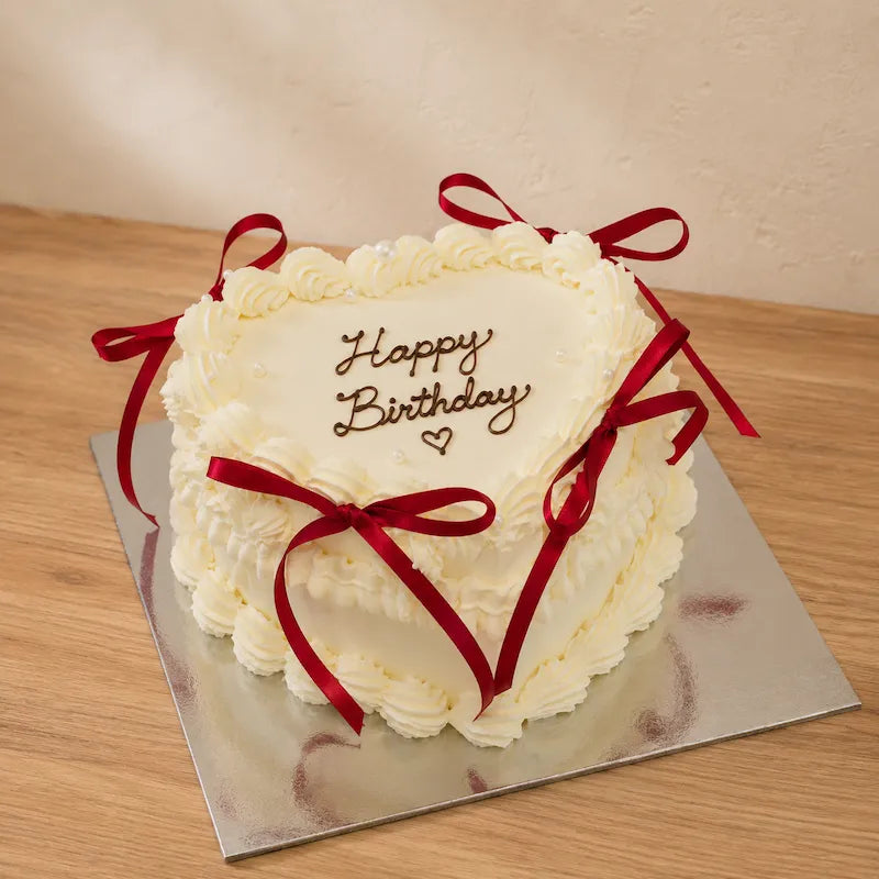 Ivory vintage heart birthday cake with red satin bows and pearl piping