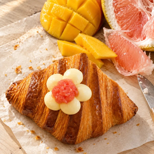 Mango Pomelo Bliss Lava Croissant topped with a mango cream flower and pink grapefruit pulp.