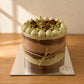 Low-angle view of Dubai chocolate naked cake with exposed filling layers and pistachio cream piping