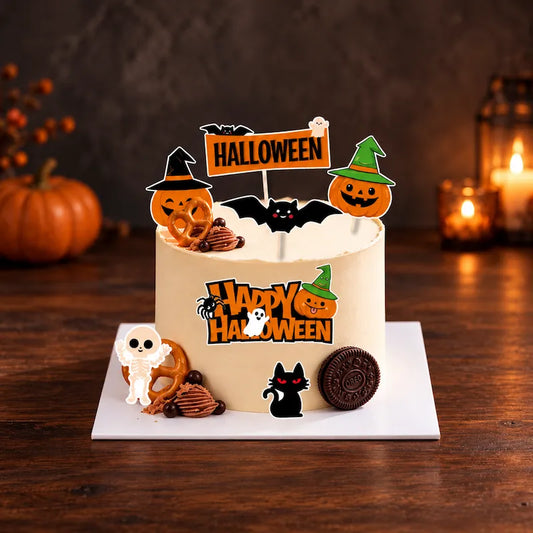 Cream-coloured Halloween cake with pumpkin and bat toppers, a ghost sign, skeleton and black cat decorations on a flat white cake board.