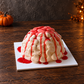 Zombie Brain Halloween Cake on a dark wooden table with a pumpkin and warm orange lights in the background.