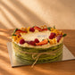 Overhead view of matcha mille crepe cake topped with strawberries, raspberries and orange slices