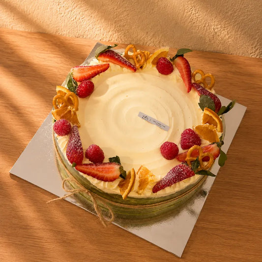 Matcha mille crepe cake with fruit and cream decorations, viewed from above at an angle